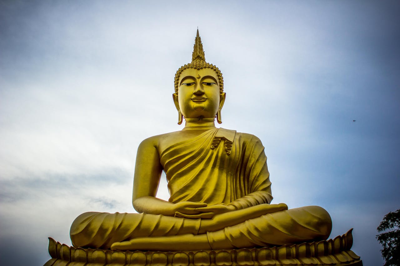 Home A majestic golden Buddha statue against a serene blue sky, symbolizing peace and spirituality.